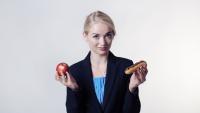 Girl holding up an apple and a hot dog.