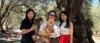 An image with Louis Wu and her family members, including two dogs, in front of trees and a picnic scene.