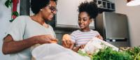 Family members unpacking groceries in a kitchen.