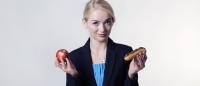 Girl holding up an apple and a hot dog.